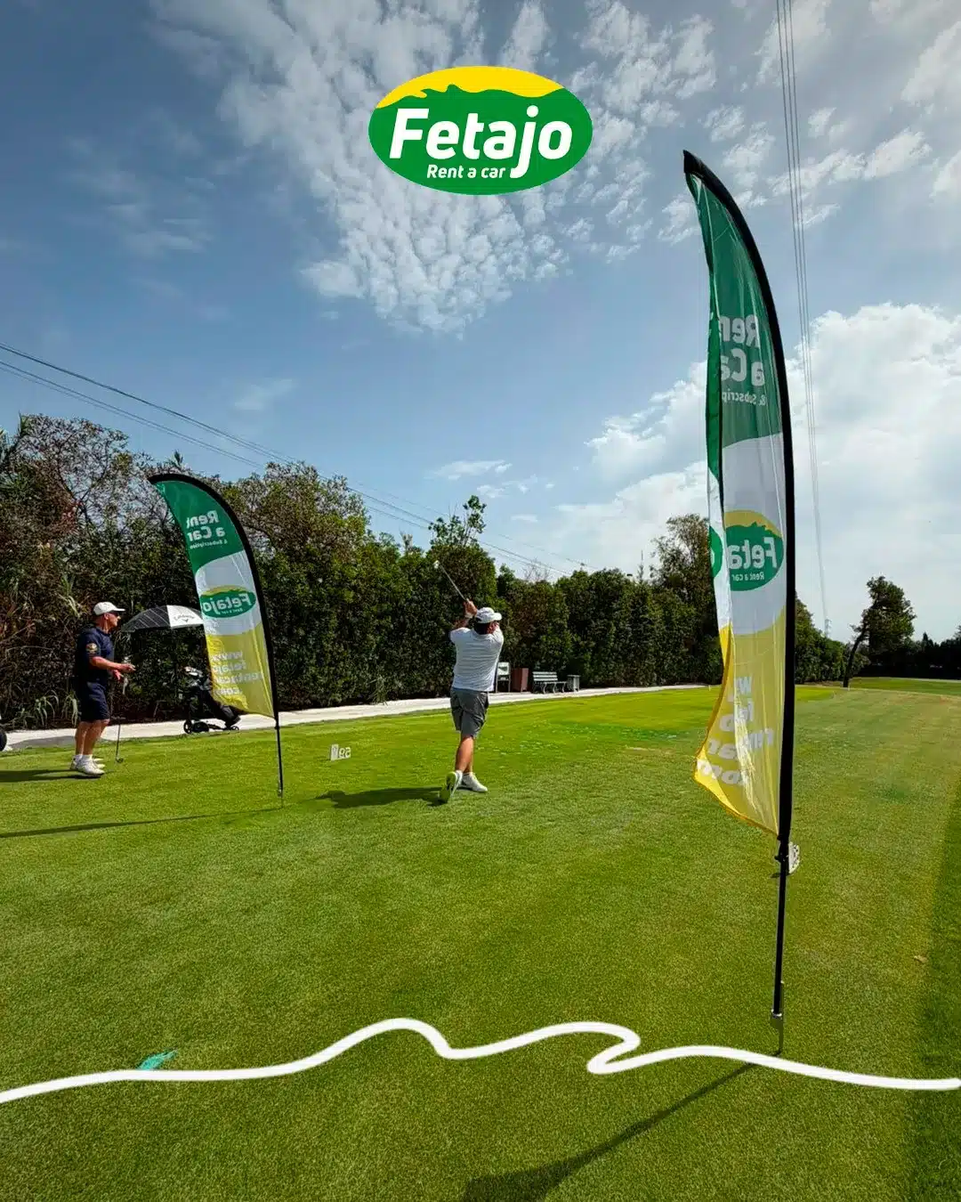 A golfer mid-swing between two Fetajo Rent a Car banners at the Atalaya Golf WAGC qualifying round