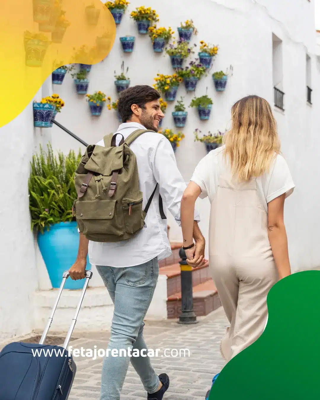 Couple walking with luggage down a whitewashed Málaga street lined with blue flower pots